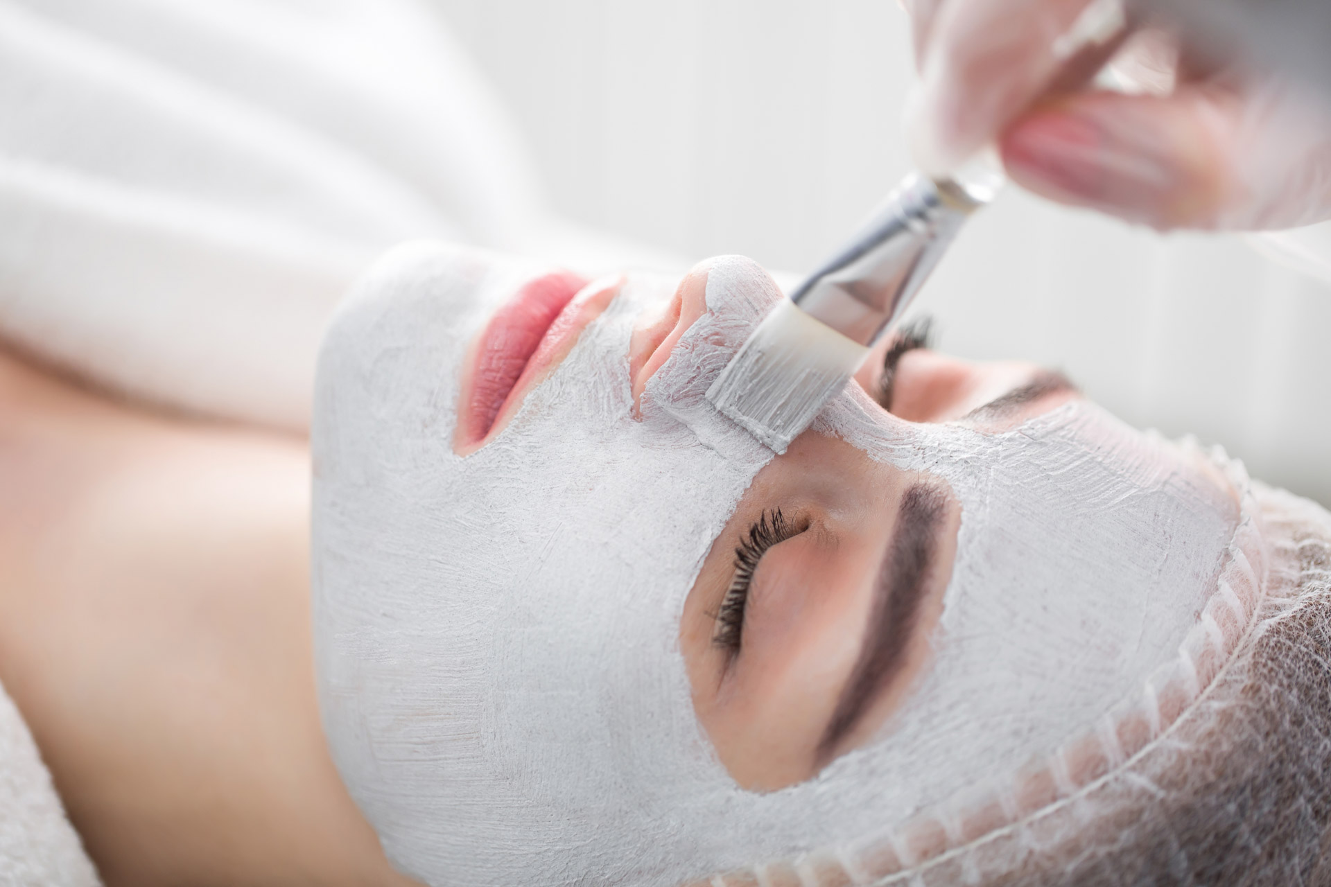 Woman getting facial care by beautician at spa salon